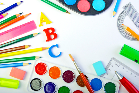 School supplies. Pencils, paints, eraser, pens, brushes and letters on a white background. Beginning of the school year. Copy spaces.の写真素材