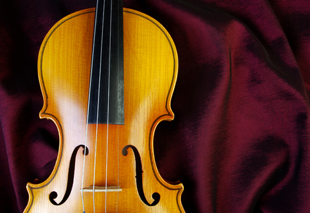 Violin on a color background. Violin on a purple silk background. Closeup.の写真素材