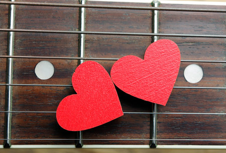 Red hearts on the strings of a guitar. Hearts are a symbol of love. Valentine's Day. Strings of the heart.の写真素材