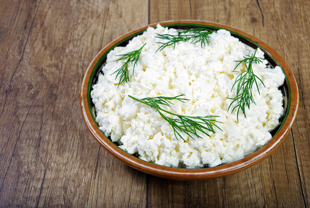 Homemade cottage cheese in a bowl on old wooden table.の写真素材