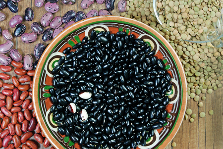 Different varieties of kidney beans and lentils on a wooden table.の写真素材