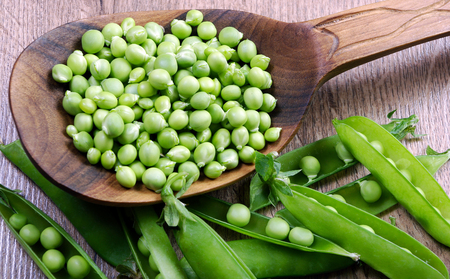 green peas in a wooden spoon. close up.の写真素材