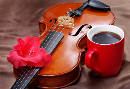 cup of coffee and a violin on a red silk backgroundの写真素材