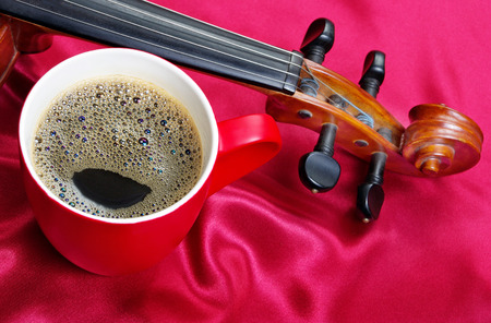 cup of coffee and a violin on a red silk background. close up.の写真素材