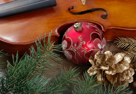 New Year background. New Year's ball, violin, branches of the Christmas tree and golden fir cones on a wooden table.の写真素材
