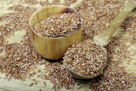 Raw seeds of flax in a wooden spoon close-up.の写真素材