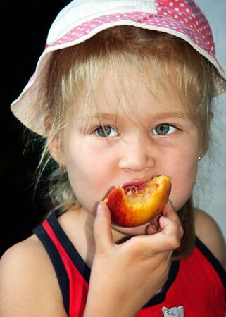 girl eating peach. natural healthy food for childrenの写真素材