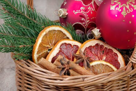 Christmas design. Christmas preparations. Christmas balls and branches of a Christmas tree in a basket. Dried citruses, cinnamon sticks and anise stars. Dried fruits and spicesの写真素材