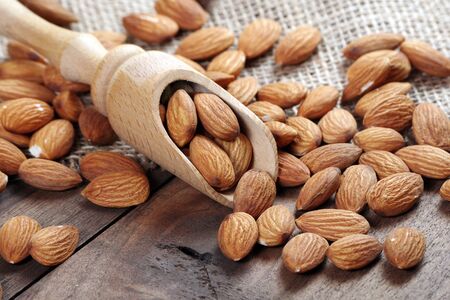 almonds in a spoon on a wooden table close-upの写真素材
