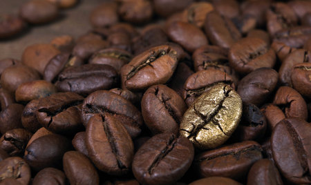 Gold coffee beans on a pile of coffee beans. The concept of luxury. Coffee beans texture background.の写真素材