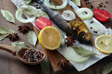 smoked fish and spices on a wooden table. smoked herring on a cutting board. top view.の写真素材
