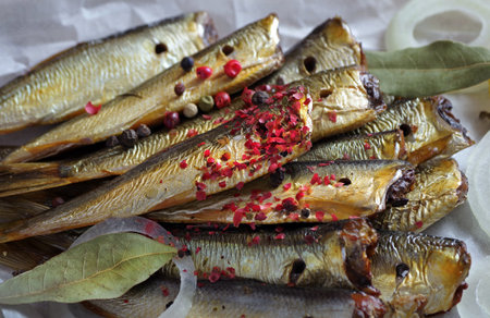 smoked fish and spices close-up. smoked sprats in pink and black pepper