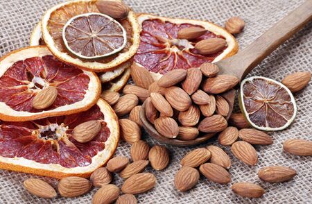 almond nuts in a spoon and dried fruits on a table close upの写真素材