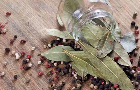 dry bay leaf in a glass jar on a wooden table. bay leaf and pepper mixture close upの写真素材