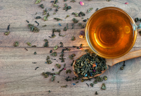 blended tea. green tea with dry flower petals. dry leaves of green tea in a wooden spoon and glass...