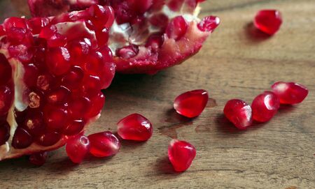 juicy ripe pomegranates on a wooden table. bright colorful pomegranate seedsの写真素材