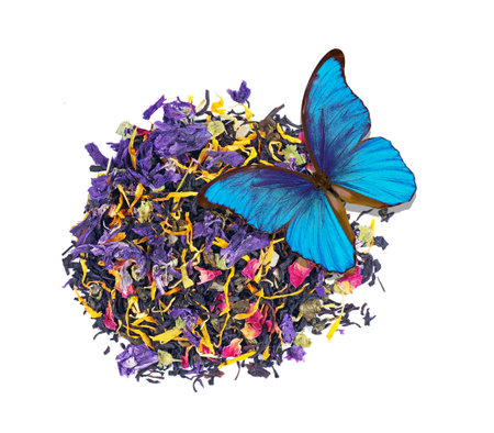 heap of tea leaves and flower petals isolated on a white. blended tea close up. beautiful blue morpho butterfly on a heap of blended tea. drink concept. top viewの写真素材