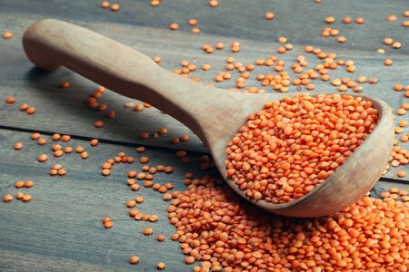 red lentils in a wooden spoon on a wooden table. close upの写真素材