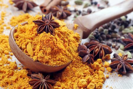 Turmeric in a wooden spoon, anise stars and cinnamon close up. traditional spicesの写真素材