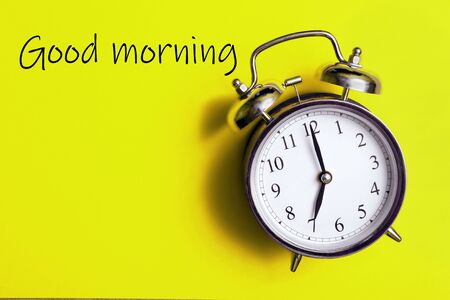 Good morning concept. Alarm clock on a yellow background. Seven o'clock in the morning. copy spaceの写真素材