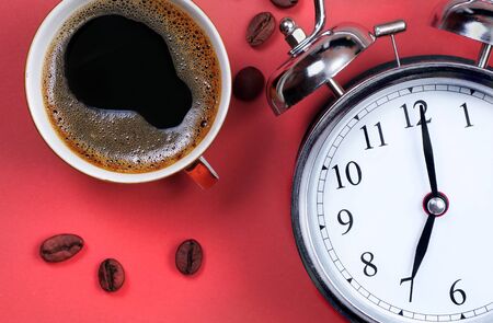 Good morning concept. Alarm clock on a red background and cup of coffee. Seven o'clock in the morning. top viewの写真素材