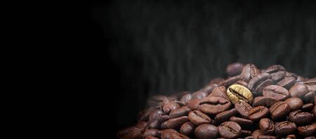 Coffee concept. Golden coffee beans in a spoon, a pile of roasted coffee beans and a cup of black coffee. concept of quality and luxury. copy spaceの写真素材