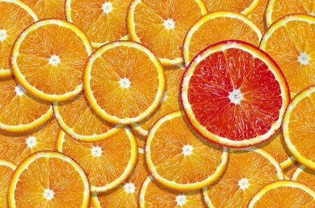 sliced orange texture background. natural orange background. slice of grapefruit on a background of slices of orange. one of many.の写真素材