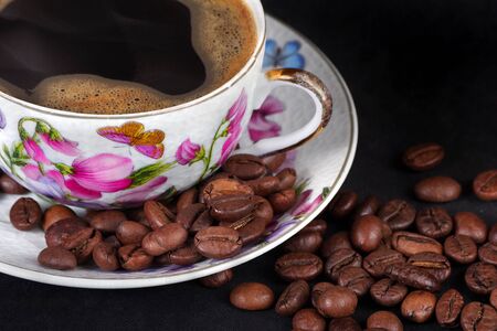 colorful cup of coffee with foam and roasted coffee beans isolated on blackの写真素材