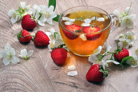 summer vitamin tea. green tea with jasmine and strawberries on a wooden table.の写真素材
