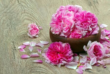 tea rose flowers in a bowl on a wooden tableの写真素材
