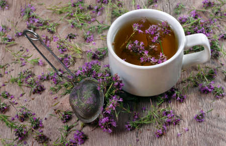 summer medicinal herbs. thyme tea on a wooden table. fresh thyme flowers in a tea strainerの写真素材