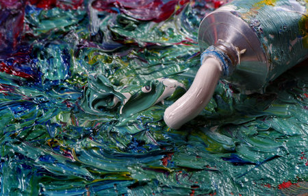 tube with white art oil paint and brush on a palette. colorful art paints close-up.