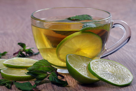 refreshing drink with mint and lime. a cup of mint tea with lime on a wooden table.