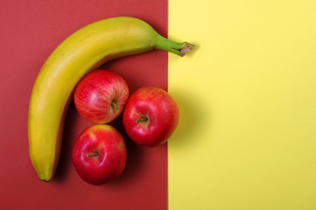 colorful fruit background. banana and apples on colored cardboard. top view. copy space