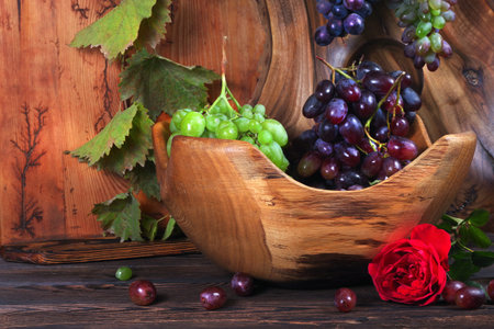 Fresh ripe grapes. Grape harvest. Handmade wooden utensils on the kitchen table. Wooden plates, bowls and dishes on the table.の写真素材