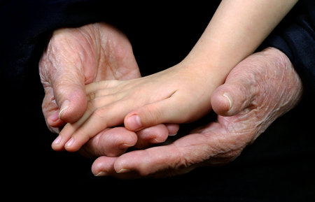 the hand of a child in the hands of a grandmother. elderly woman's hands and baby's hand.
