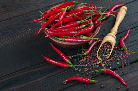 red hot chili peppers and a mixture of peppers in a wooden spoon on a wooden table. top view. traditional spices.の写真素材