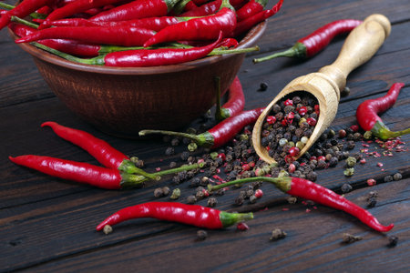 red hot chili peppers and a mixture of peppers in a wooden spoon on a wooden table. pepper mixture....