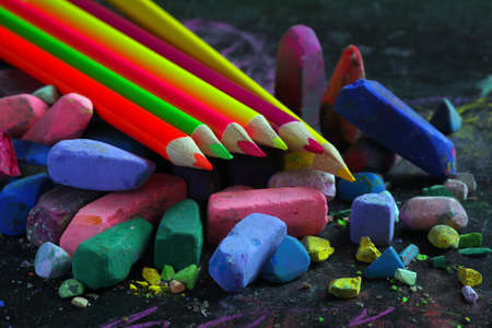 multicolored pastel crayons and colored pencils on black drawing board close upの写真素材