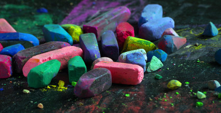 multicolored pastel crayons on black chalkboard close up
