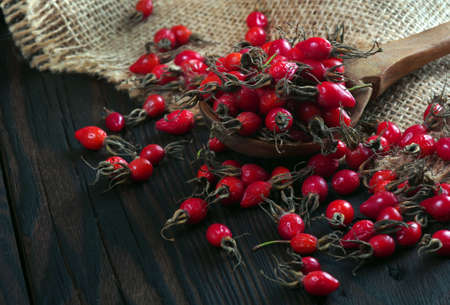 ripe red rose hips on a wooden table. dog-rose fruit close upの写真素材