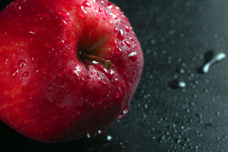 red ripe apple in drops of water on the table. copy space