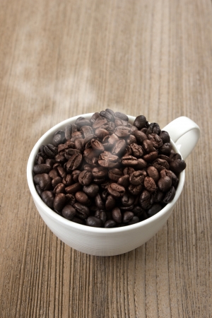 Coffee beans and coffee cup on a wooden floor.の写真素材