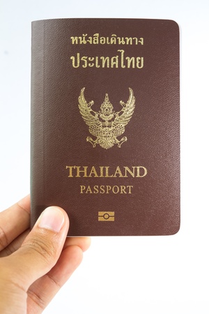 Thailand Passport in human hand isolated on white backgroundの写真素材