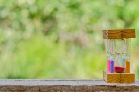 Hourglass on wooden table on blurred natural background