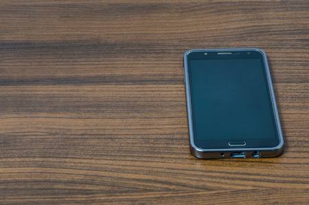 Black smartphone with blank screen mock up above wooden table backgroundの写真素材