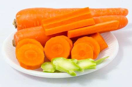 Carrot slices and kale slices on white plastic dish isolated on white backgroundの写真素材