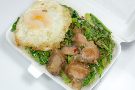Steamed rice top with stir-fried Kale with crispy pork belly, on top with fried eggの写真素材