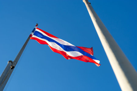 Image of waving Thai flag of Thailand with blue sky background.