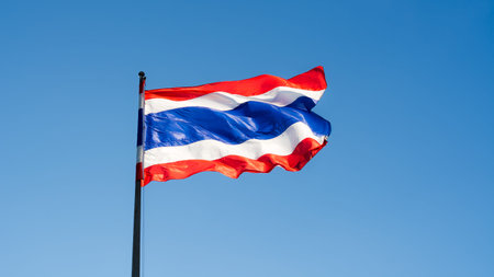 Image of waving Thai flag of Thailand with blue sky background.